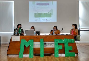 Jessica Bibao, Maria del Carmen Alvarez,  Micaela Zuconni detras de la mesa, adelante el letras grandes y verdes las letras MI FE