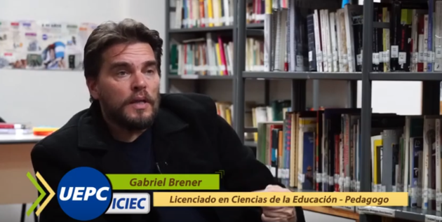 Captura de pantalla de la entrevista a Gabriel Brener. Se ve al entrevistado de frente, mirando a la cámara con un videograph que dice "Licenciado en Ciencias de la Educación - Pedagogo".
