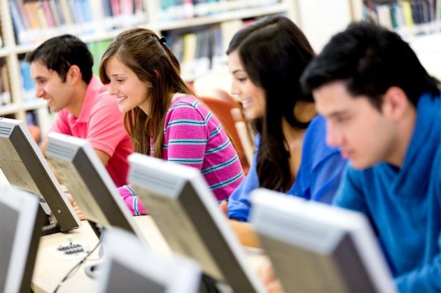 Grupo de estudiantes en una biblioteca, trabajando en computadoras de escritorio
