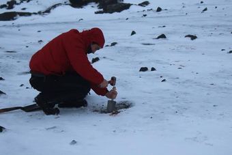 Investigador tomando muestra en suelo antártico